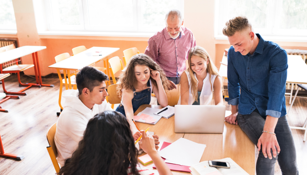 groupe d'élèves en pleine discussion avec un professeur autour d'un ordinateur